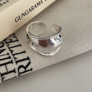 Macro shot of irregular minimalist silver wide band open ring on aesthetic fabric