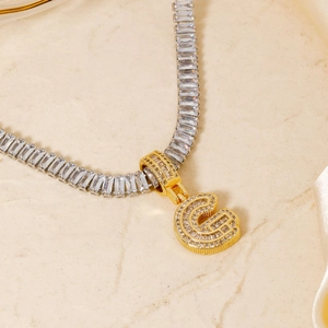 Detailed close-up of a luxury gold G-letter pendant with emerald-cut zirconia stones