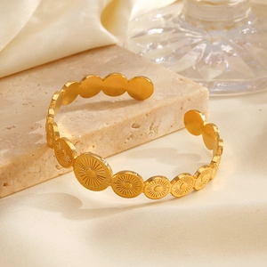 Elegant gold stainless steel geometric circular bangle on a beige marble base