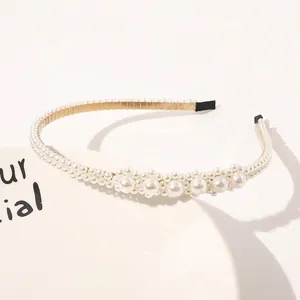 Detail of elegant pearl headband with gold metal frame and white pearls on ceramic tray