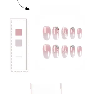 Detail of pink and white gradient press-on nails with floral art and rhinestones