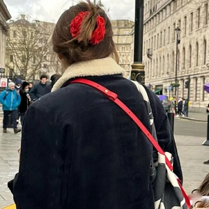 Detail of red rose floral hair claw clip on brunette hair with stylish outdoor street view