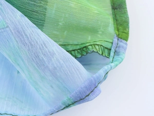 Makroaufnahme von Chiffonstoff mit Seerosenmuster in Grün und Lila und sauberem Saum