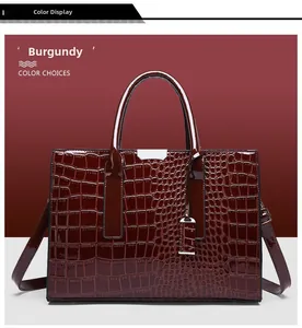 Detail view of burgundy crocodile-embossed handbag with glossy finish and metal buckle