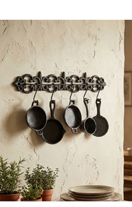 Détail d'un support mural de cuisine vintage en fonte avec cinq modèles de mini ustensiles