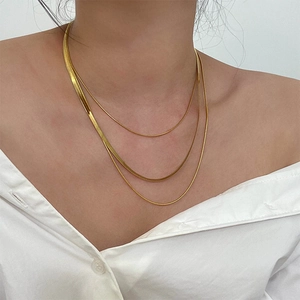 Three-layer gold titanium steel snake chain necklace set worn by a model on white shirt
