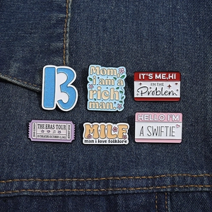 Detail view of six Taylor Swift themed enamel pins arranged on blue denim fabric