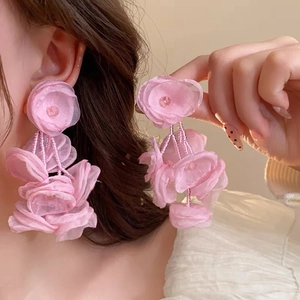Close-up of pink layered mesh flower tassel earrings worn by a model in soft light