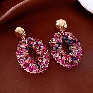 Detailed view of handmade colorful glass bead oval earrings on brown fabric background