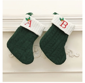 Détail de chaussettes de Noël en tricot vert avec lettres A et B brodées sur une cheminée
