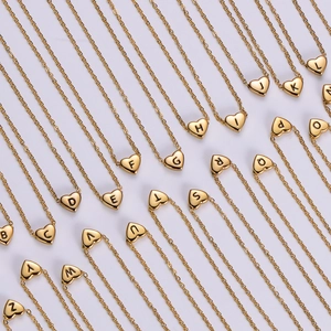 Macro view of solid gold plated heart necklaces featuring various engraved alphabet letters