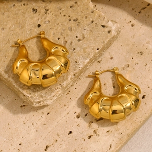 Detailed view of gold plated stainless steel chunky croissant earrings on stone surface