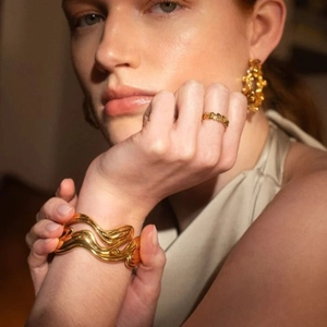 Detailed view of 18k gold plated wave textured bracelet ring and circular earrings set