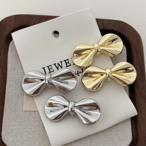 Set of four small metallic bow hair clips in polished gold and silver finishes