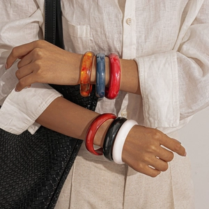 Detailed shot of resin bangles in amber, blue, red, black, and white on a model's wrist