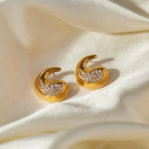 Macro shot of 18k gold plated teardrop earrings with crystals on white silk fabric