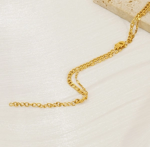 Detail of golden Hamsa hand charm on a dual-layer Figaro chain and bead wrist jewelry