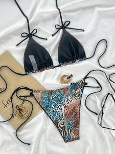 Flat lay of a leopard print patchwork bikini set with sunglasses on a white textured background