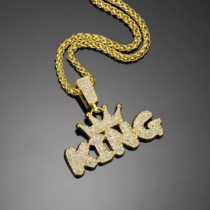 Macro detail of iced-out gold KING crown pendant with shimmering crystals on twist chain
