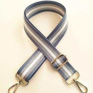 Close-up of blue and silver striped wide bag strap with gold metal lobster clasps
