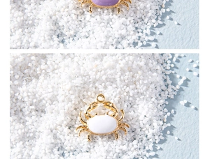 Close-up of purple and white enamel crab charms with gold plating for DIY jewelry