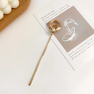 Gold metal hair pin with minimalist double interlocking rings on an aesthetic background