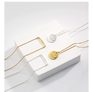 Detail of minimalist gold and silver stacked necklaces with hammered disc pendants