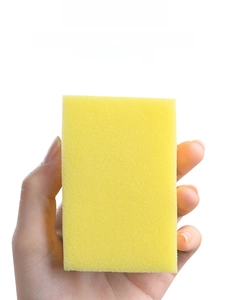Macro shot of rectangular yellow cleaning sponge with porous texture held in hand