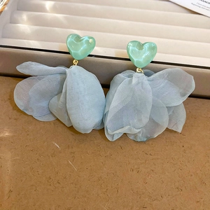 Detail view of heart-shaped green studs and layered light blue tulle floral drop earrings