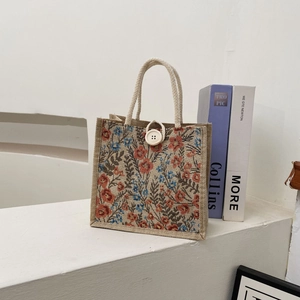 Close-up of floral linen lunch tote bag with coarse rope handles and white button closure