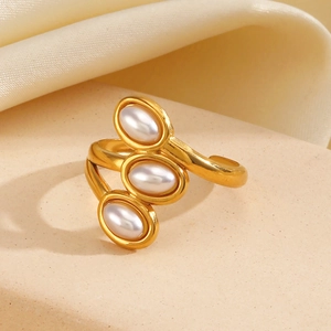 Vintage adjustable gold ring with three white oval pearls on beige silk background