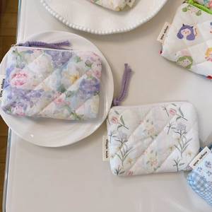 Close-up of quilted floral coin purses with zipper closures and simple wish fabric labels