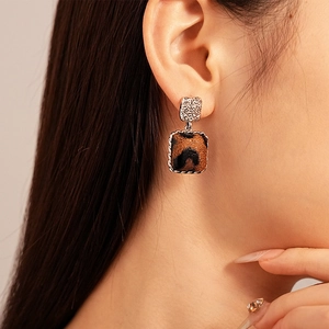 Close-up of square leopard print earrings with vintage silver twisted rope borders