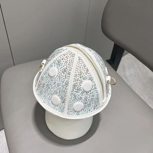 Detail view of mushroom-shaped white handbag with sparkling rhinestones and gold hardware