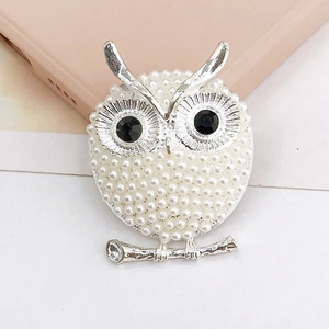 Detail of silver owl charm with white pearls and black rhinestone eyes on a branch
