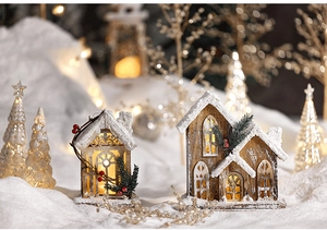Detail of glowing wooden Christmas houses with artificial snow and warm LED lights decor