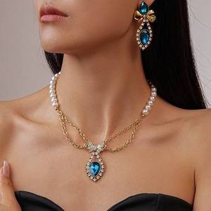Close-up of vintage pearl necklace with bowknot and blue gemstone waterdrop pendant
