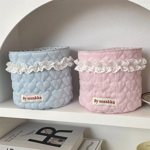 Close-up of heart-quilted fabric storage baskets with white lace trim and textile label
