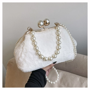 Detailed view of white plush handbag with gold clasp and pearl shoulder straps on sofa
