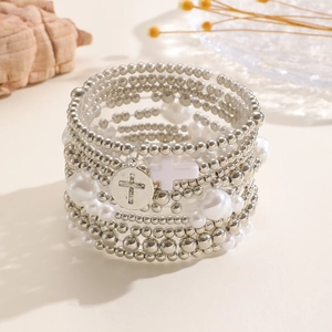Dettaglio di braccialetti boho con perline e ciondoli a croce su vassoio a conchiglia
