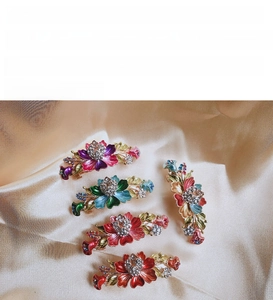 Close-up of enamel flower hair clips with colorful rhinestones on satin fabric