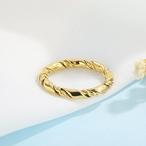 Detailed view of a golden twisted ring featuring a double-layer design on a soft fabric