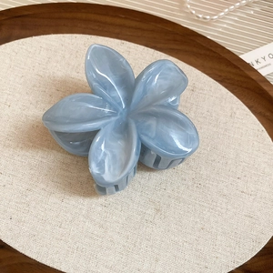 Détail d'une pince à cheveux fleur bleu marbré sur lin et plateau en bois décoratif