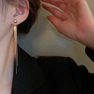 Close-up of elegant gold tassel long drop earrings worn by a model in soft lighting