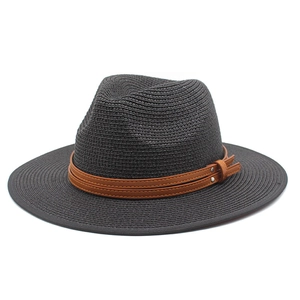 Détail d'un chapeau Panama noir en paille avec bande en cuir marron et rivets métalliques