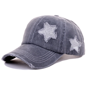 Detail of washed grey denim baseball cap featuring silver glitter star and distressed brim