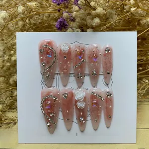 Detailed view of pink marble press-on nails with 3D white flowers and sparkling rhinestones