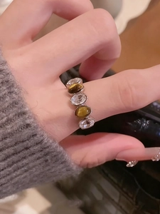 Macro detail of silver ring featuring tiger eye stones and zircons on fingers