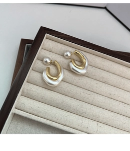 Detail view of gold metal and pearl resin earrings on a vintage jewelry display tray