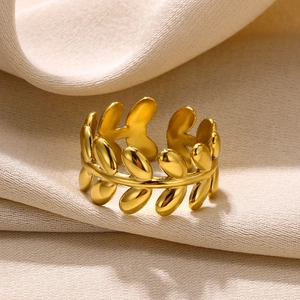 Detailed close-up of a polished gold leaf open ring on a textured fabric background